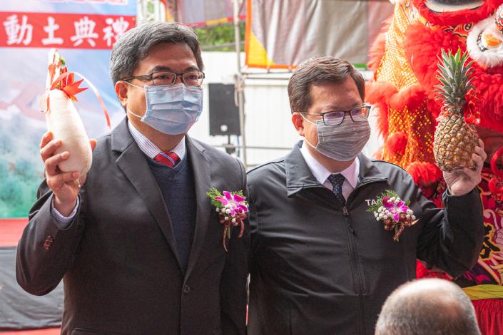 市長和與會人員手持鳳梨和蘿蔔合影，象徵好彩頭