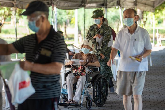 後備指揮部服務團隊協助行動不便的長輩完成報到手續