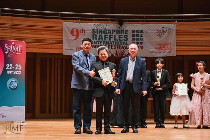 樂亮青年絃樂團指揮劉志清在閉幕音樂會中領取「特別榮譽金獎 Gold with Honours」獎盃與獎牌。照片提供：新加坡佛萊士國際音樂節。