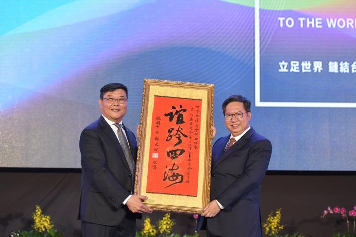 桃園市長鄭文燦(右)贈給世界台灣商會聯合總會第25屆總會長游萬豐「誼跨四海」裱框掛軸。