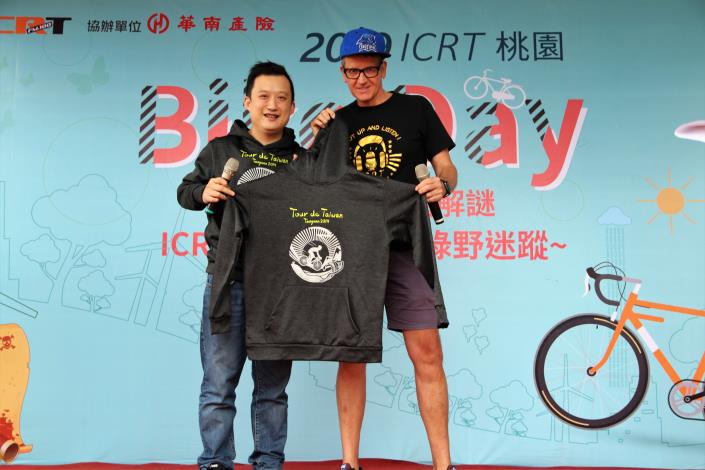 桃園市府秘書處長顏子傑(左)贈給ICRT總經理白健文2019國際自由車環台公路大賽帽T。