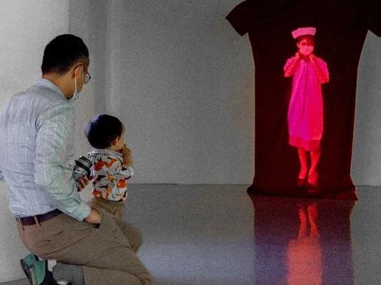 「夢不落展」親子觀看許惠晴《邊境漫遊》空間錄像裝置，反思、審視「空服員」職業所反映的社會、政治及性別思索