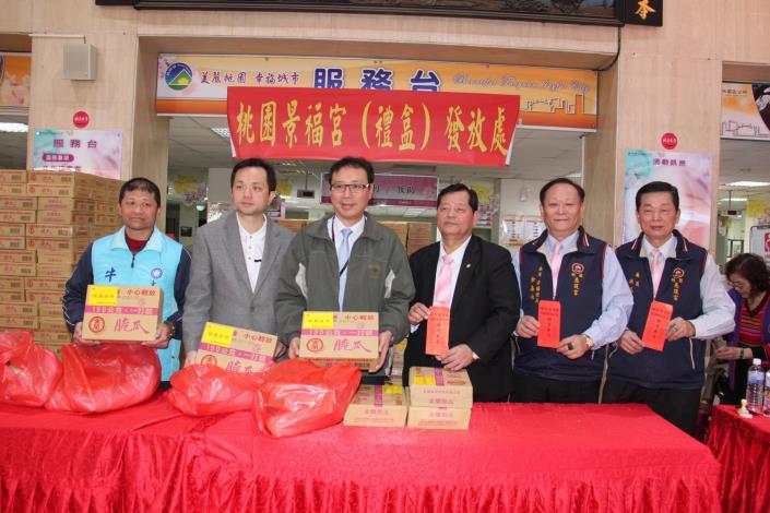 桃園市政府首席顧問黃適卓、桃園區長張世威、桃園慈護宮主委劉新發等人，拿著待發送紅包及民生物資合影。